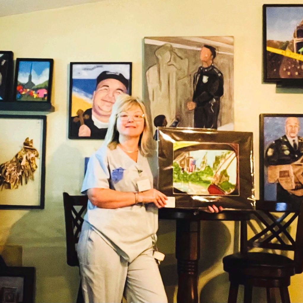 Lisa Domenic in gallery pointing to artwork